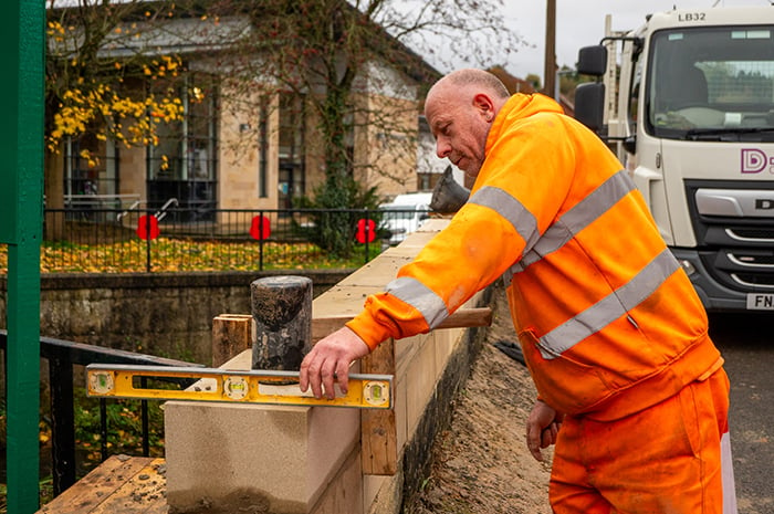 A workman uses a spirit level on new stonework on Henmore Bridge