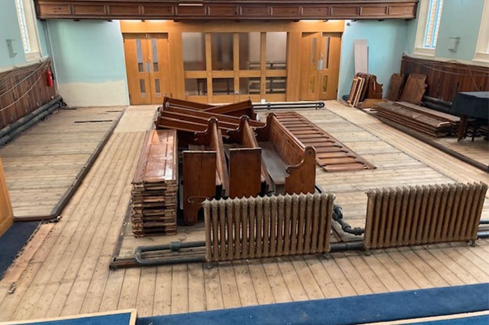 Dismantled wooden pews and cast iron radiators in the centre of the stripped-out hall at Ashbourne Methodist church