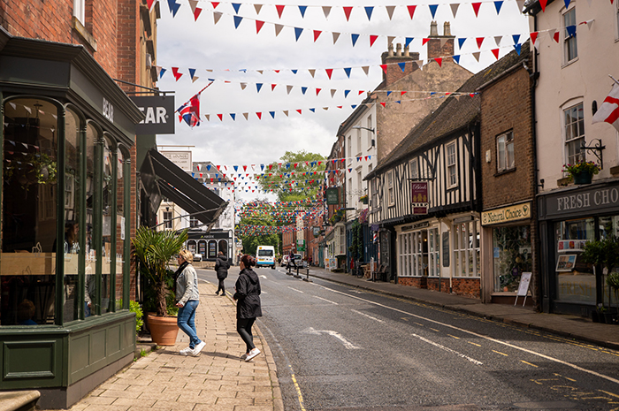 Red, white and blue bunting hangs across a sunny St John Street as two women walk into a coffee shop